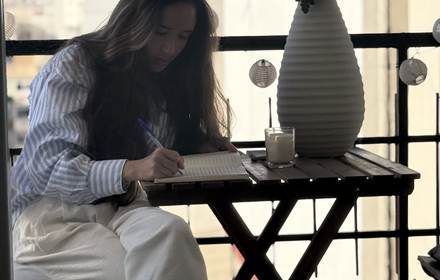 Andrea escribiendo a mano en una mesa junto a la ventana